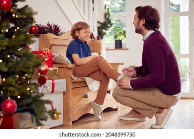 Father Helping Son To Tie Shoe Laces In Home Decorated For Christmas - Powered by Shutterstock