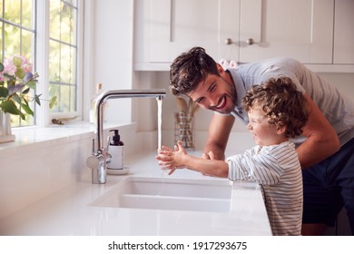 Father Helping Son To Wash Hands With Soap At Home To Stop Spread Of Infection In Health Pandemic