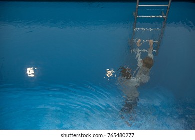 Father Helps Child Climb The Ladder Under Water In Swimming Pool