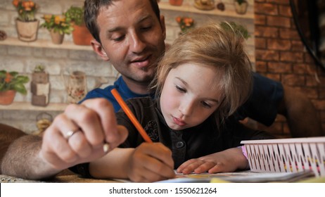 A father helps his daughter draw a drawing.