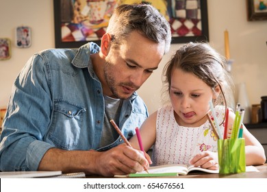A father helps his little daughter to do her homework for the school 