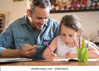 A father helps his little daughter to do her homework for the school. - Powered by Shutterstock