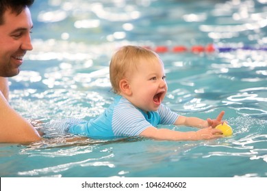 A Father Helps Is Infant Daughter During Swimming Lessons In The Pool.