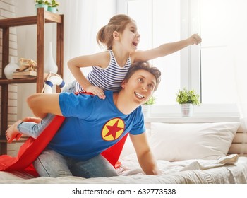 Father And His Child Playing Together. Girl And Dad In Superhero Costume. Daddy And Kid Having Fun, Smiling And Hugging. Family Holiday And Togetherness.