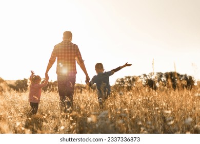 Father and his children walking in a field at sunset enjoying time together in nature  - Powered by Shutterstock