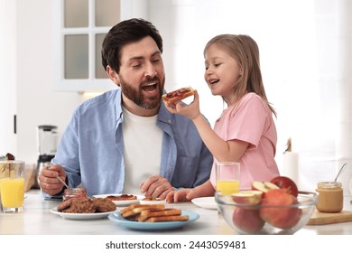 Father and his cute little daughter having fun during breakfast at table in kitchen - Powered by Shutterstock