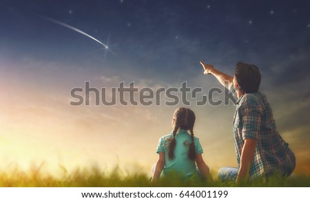 Father and his daughter are looking at falling star.