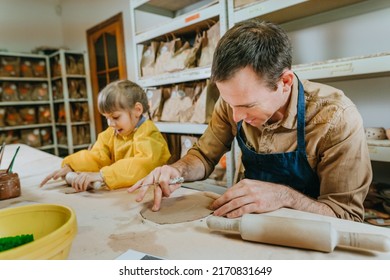 Father and his daughter at a master class of pottery clay modeling in the workshop. Young man and little girl working with clay. Happy family leisure. Idea for DIY family activity. - Powered by Shutterstock