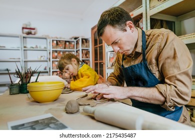 Father and his daughter at a master class of pottery clay modeling in the workshop. Young man and little girl working with clay. Happy family leisure. Idea for DIY family activity. - Powered by Shutterstock