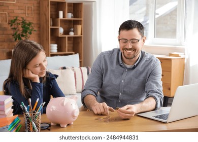 Father and his daughter with piggy bank counting money at home. Tuition fees concept - Powered by Shutterstock