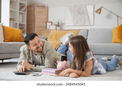 Father and his daughter with piggy bank counting money at home. Tuition fees concept - Powered by Shutterstock