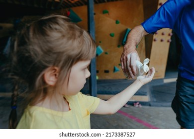 Father And His Daughter Training In A Modern Indoor Rock Climbing Gym. Male Instructor Giving Little Girl Preschooler Liquid Chalk Used To Improve Grip. Family Sport Activities. Selective Focus.