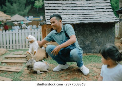 a father and his daughter were playing with several rabbits - Powered by Shutterstock