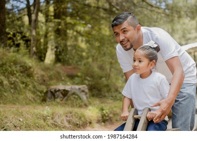 Father with his Hispanic little daughter playing on the seesaw in the park-girl having fun her father in the natural park - Powered by Shutterstock