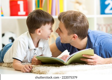 Father And His Kid Son Reading A Book On Floor At Home