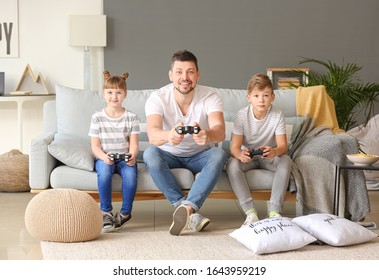 Father And His Little Children Playing Video Games At Home