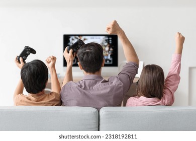 Father with his little children playing video game at home, back view - Powered by Shutterstock