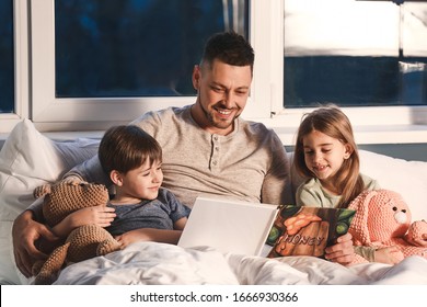 Father and his little children reading bedtime story at home