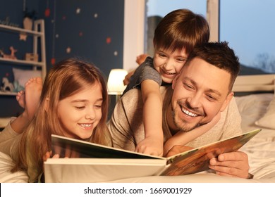 Father And His Little Children Reading Bedtime Story At Home