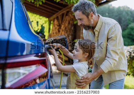Father with his little daughter charging their electric car.