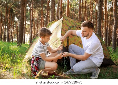 Father and his little son putting up camping tent in forest - Powered by Shutterstock