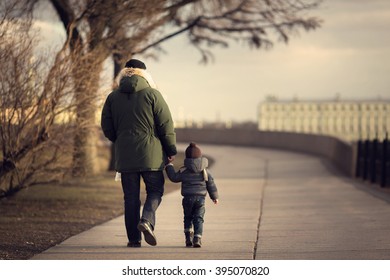 Father and his little son are walking at the Neva quay at sunset in spring Saint-Petersburg, Russia. Image with selective focus and toning