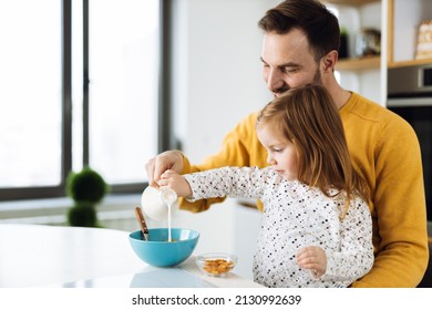 Father and his small girl  having cereal for breakfast  in the kitchen  while they pouring  milk into the bowl - Shutterstock ID 2130992639
