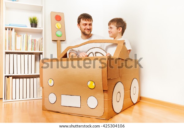 Father and his\
son driving handmade cardboard\
car
