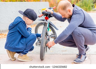 Father And His Son Fixing Bike In A Park