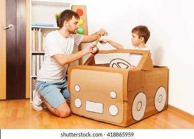 Father And His Son Making Toy Car Of Cardboard Box