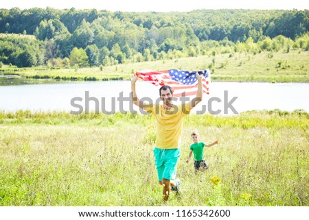 Father with his son in nature and the American flag. Patriotic holiday. Happy family. USA celebrate 4th of July