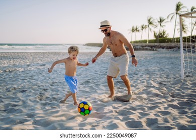 Father with his son plaing football on the beach. - Powered by Shutterstock