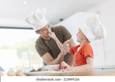 a father and his son preparing a cake in the kitchen