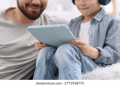Father and his son using tablet at home, closeup