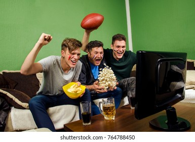 Father And His Sons Celebrating Touchdown, Watching American Football / Super Bowl On TV