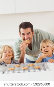Father and his sons eating cookies in the kitchen