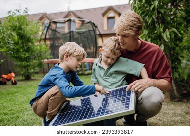 Father and his sons holding solar panel in the garden, learning about photovoltaics and green energy. - Powered by Shutterstock