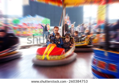 Father and his two sons,l having a ride in the bumper car at the amusement park