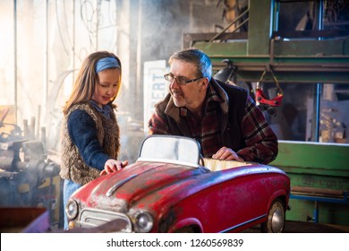 Father and his young daughter in a DIY workshop to repair an old fashioned pedal car - Powered by Shutterstock