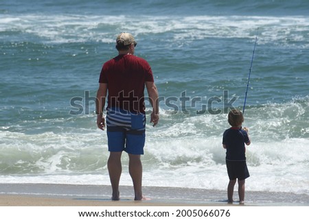 A father and his young son fish in the ocean. 