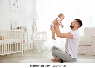 Father Holding Baby Daughter Up In The Air At Home