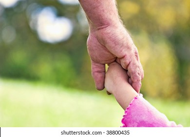 Father holding daughter's hand with bokeh in background in the shape of a heart. Could also be used as grandfather's hand.