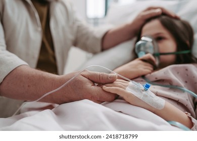 Father holding hand of his daughter in hospital bed. Child patient with an oxygen mask in ICU. - Powered by Shutterstock