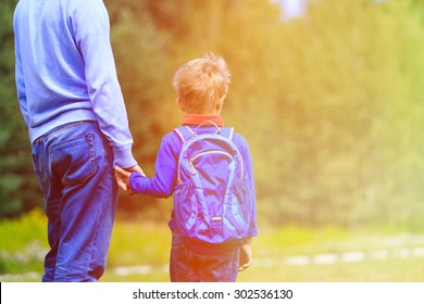 Father Holding Hand Of Little Son With Backpack Outdoors, Back To School