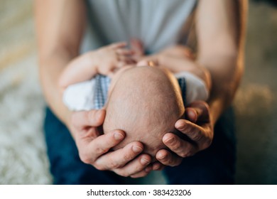 Father Holding Head Of His Newborn Son In Hands. Loving Father Hand Holding Cute Sleeping Newborn Baby Child