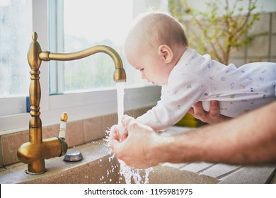 Father Holding His Little Baby Girl And Helping Her To Wash Hands