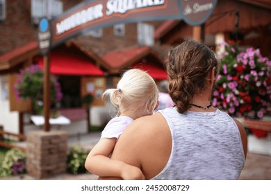 A father is holding his little girl daughter and they have matching ponytails and are walking into an outdoor summer market. - Powered by Shutterstock