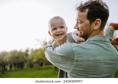 Father holding little baby, playing, having fun during warm spring day. Father's day concept. - Powered by Shutterstock