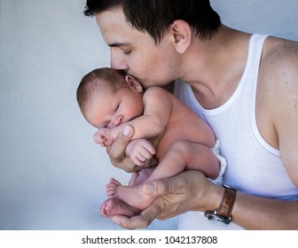 Father Holding New Born Baby Close Kissing His Head.