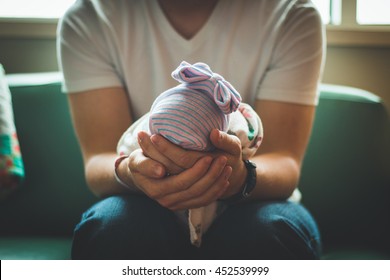 Father Holding Newborn Baby In Hospital In Front Of Window Back Lit